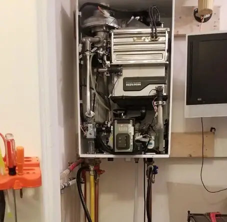 Technician servicing a wall-mounted boiler