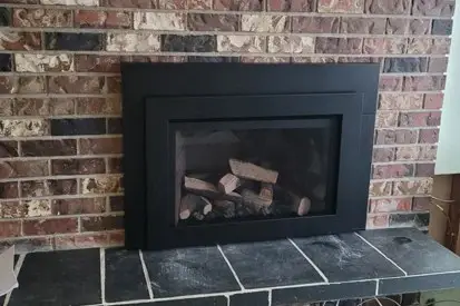 Gas fireplace insert with logs and a black surround
