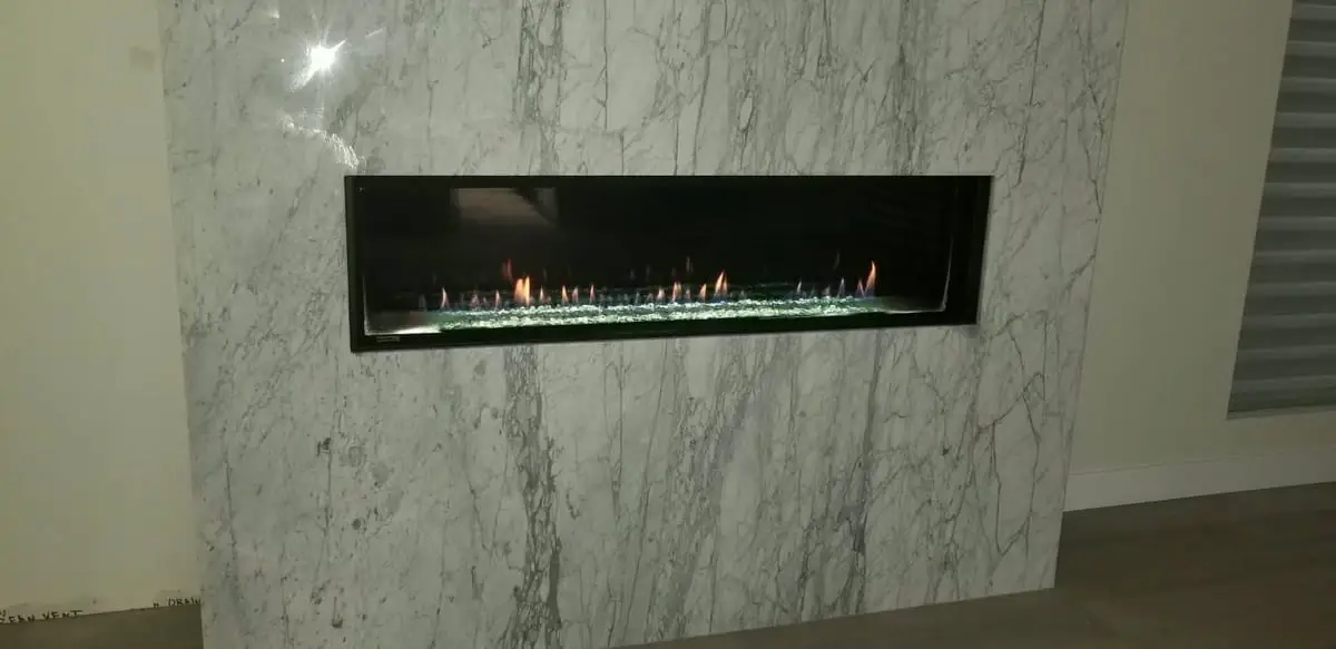 Linear gas fireplace in a marble feature wall