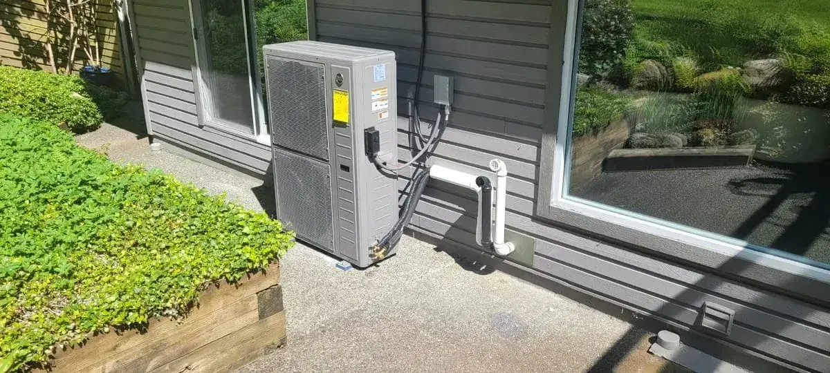 Heat pump installed on a patio beside a house