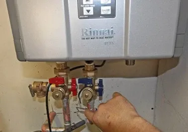Technician connecting the gas and water lines on a tankless water heater